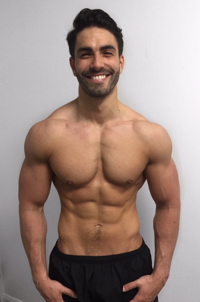 A man after his fitness transformation, standing against a white background, showcasing a muscular and toned physique.