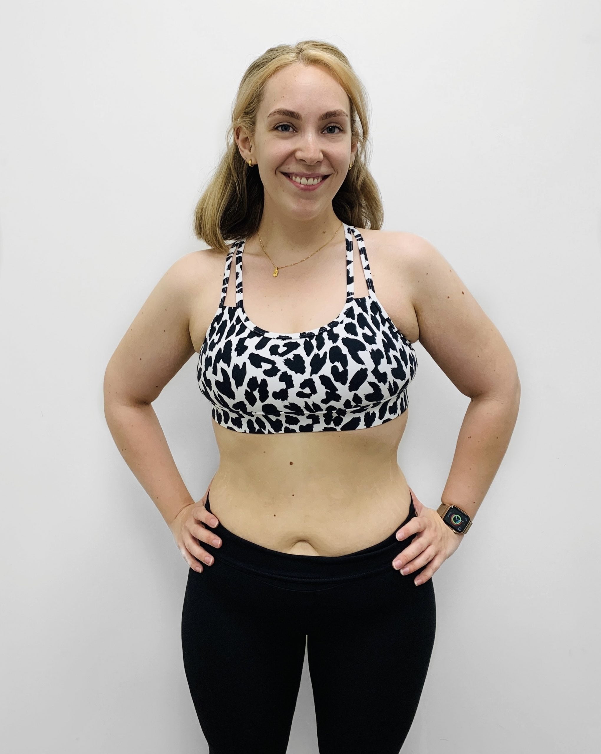 A woman after her weight loss transformation, standing against a white background, showcasing a toned and confident physique.