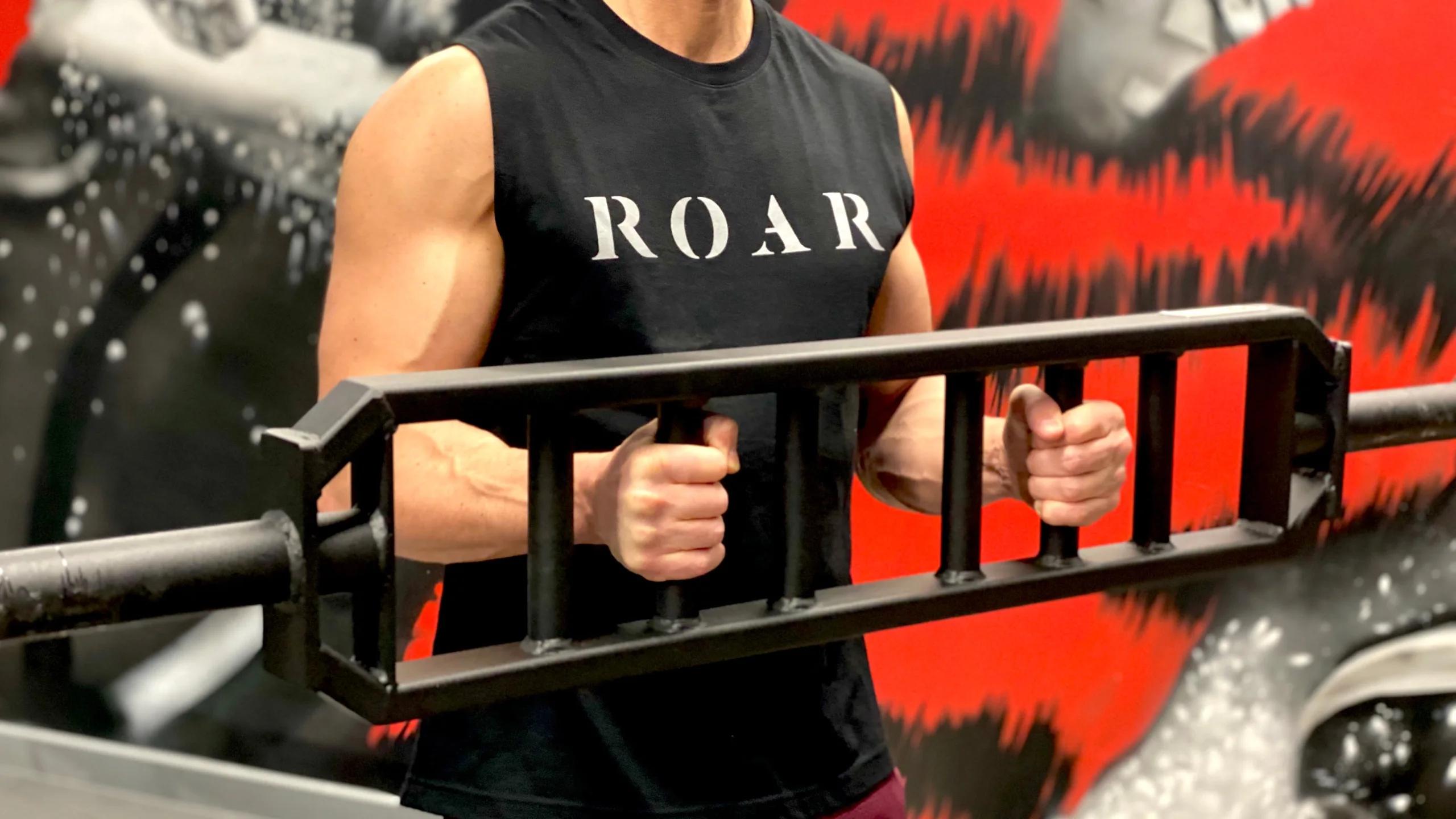 Roar Fitness client in a ROAR vest holding a multi-grip bar during a muscle building session