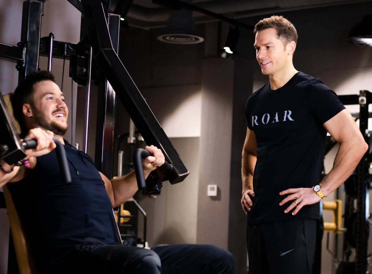Rich Phillipps providing personal training to a client performing a chest press exercise.