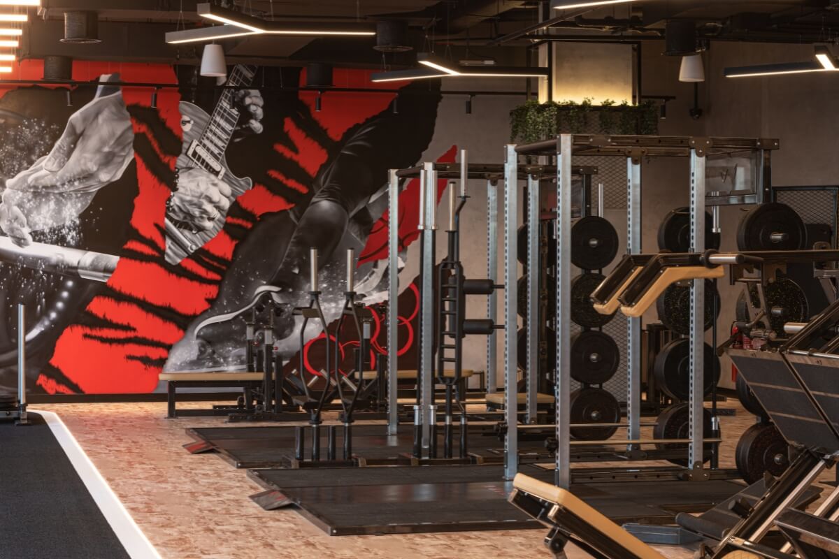 Squat racks and lifting platforms in front of the mural at Roar Fitness Dubai